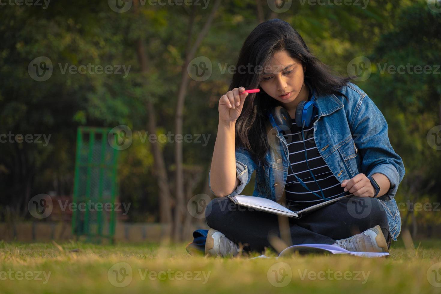 indisk student på campus full storlek bild läser böcker och tittar på kamera foto