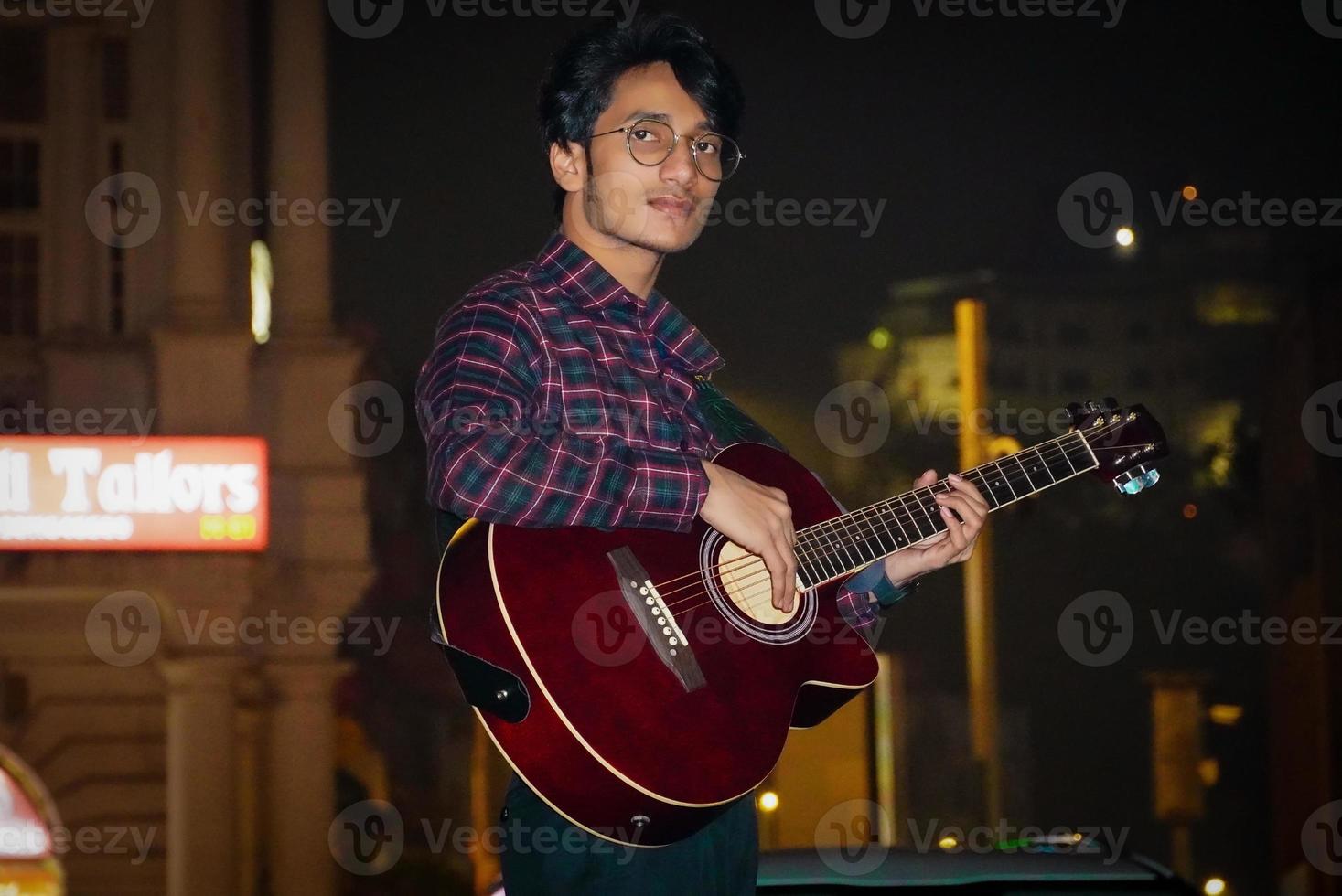 stilig gitarrist som spelar sin akustiska gitarr foto