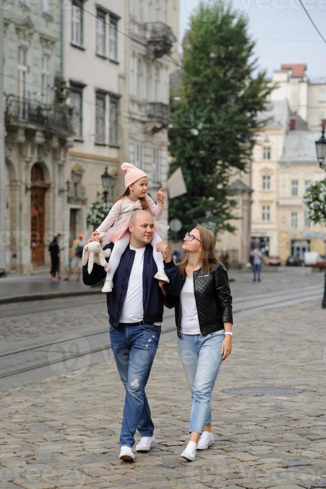 föräldrar och deras dotter sitter på trappan till en gammal kyrka. foto