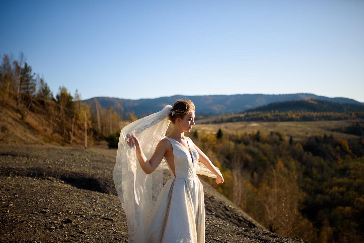 porträtt av en ung vacker brud i bergen med en slöja. vinden utvecklar en slöja. bröllopsfotografering i bergen. foto