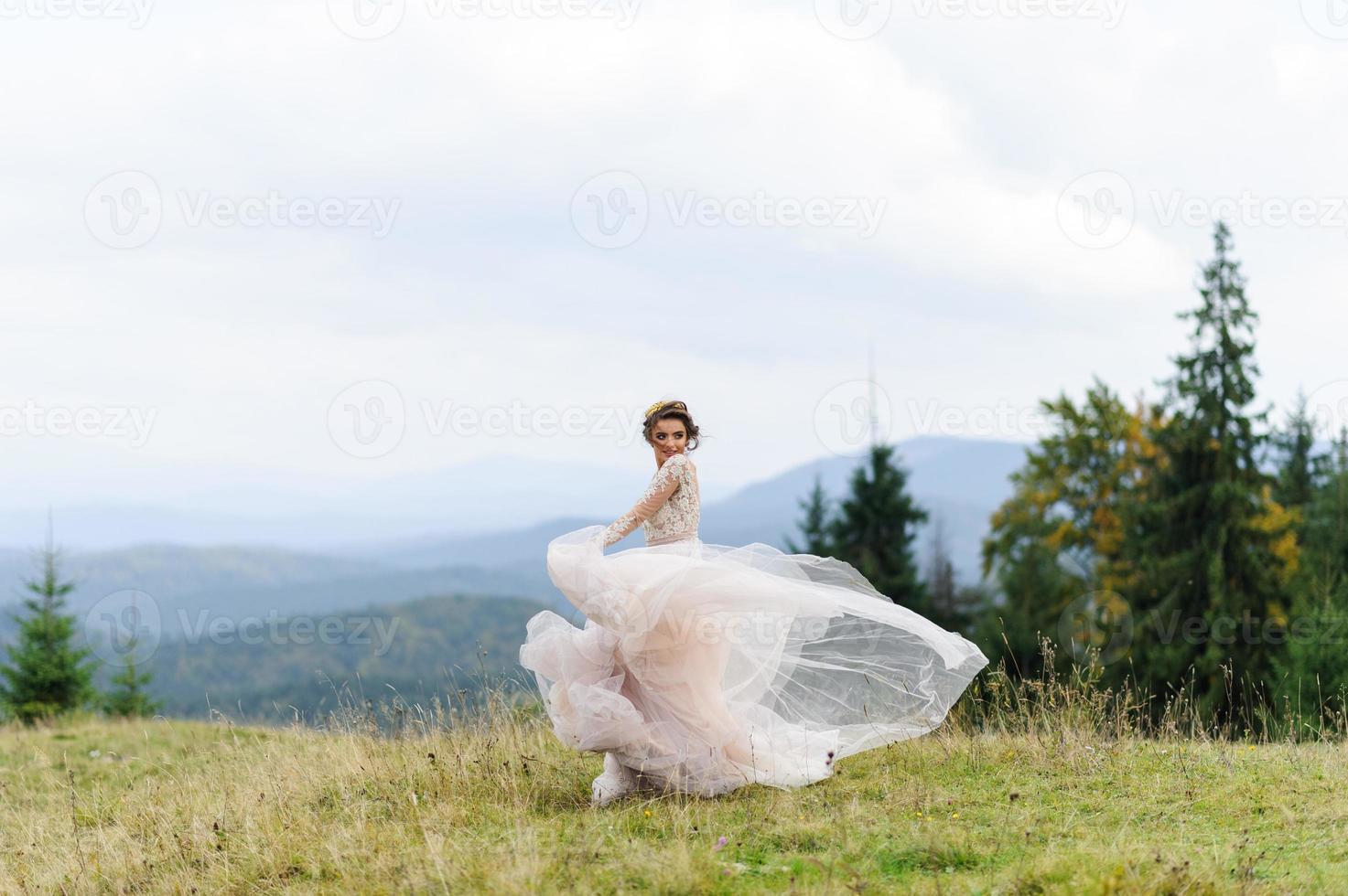bruden i en rosa luftig klänning virvlar runt och leker med sin klänning. foto