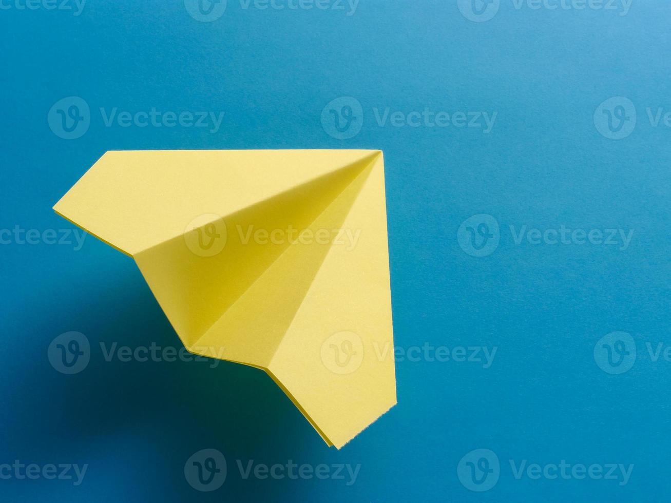 gul origami stridsflygplan på blå bakgrund. foto