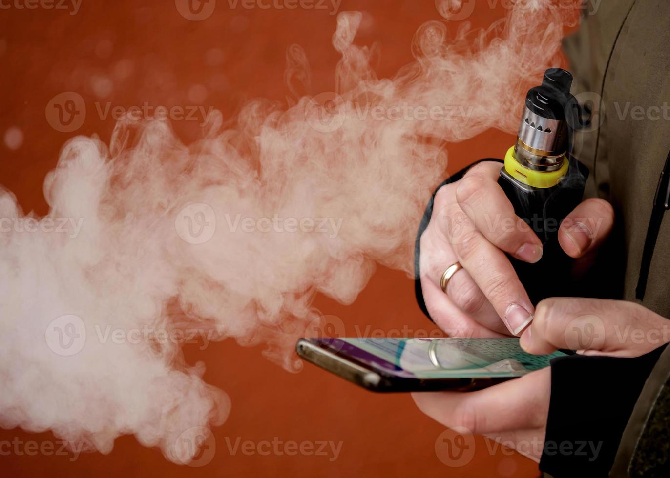 en man röker en elektronisk cigarett. vape låter röka foto
