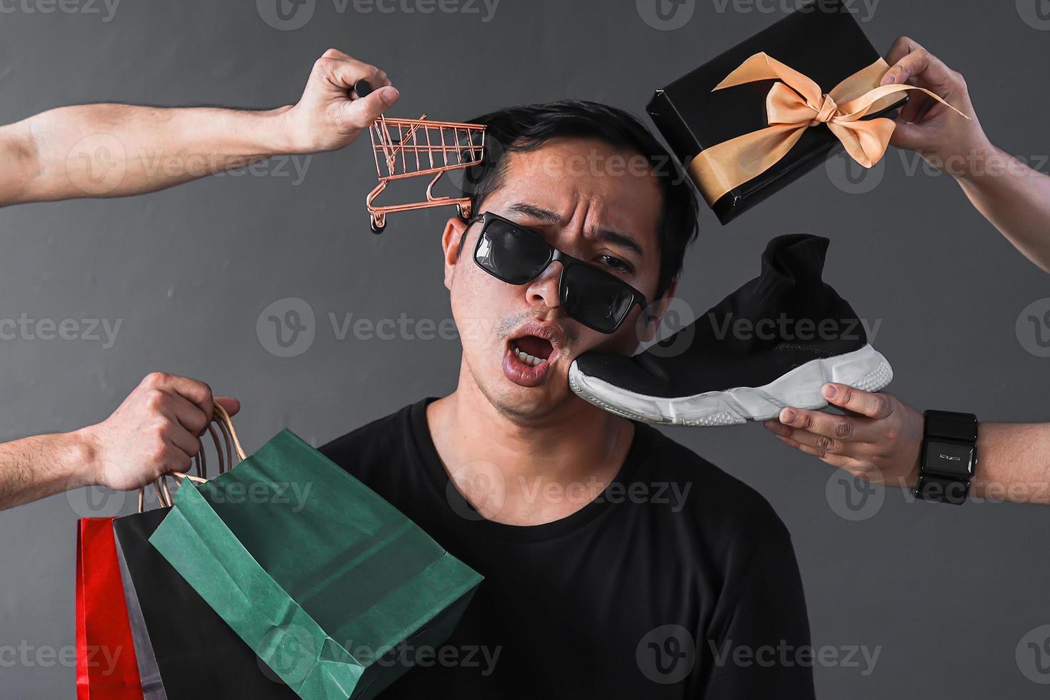 rolig online shopping säljfrämjande med fånigt uttryck shopaholic man omgiven av shopping varor och tillbehör foto
