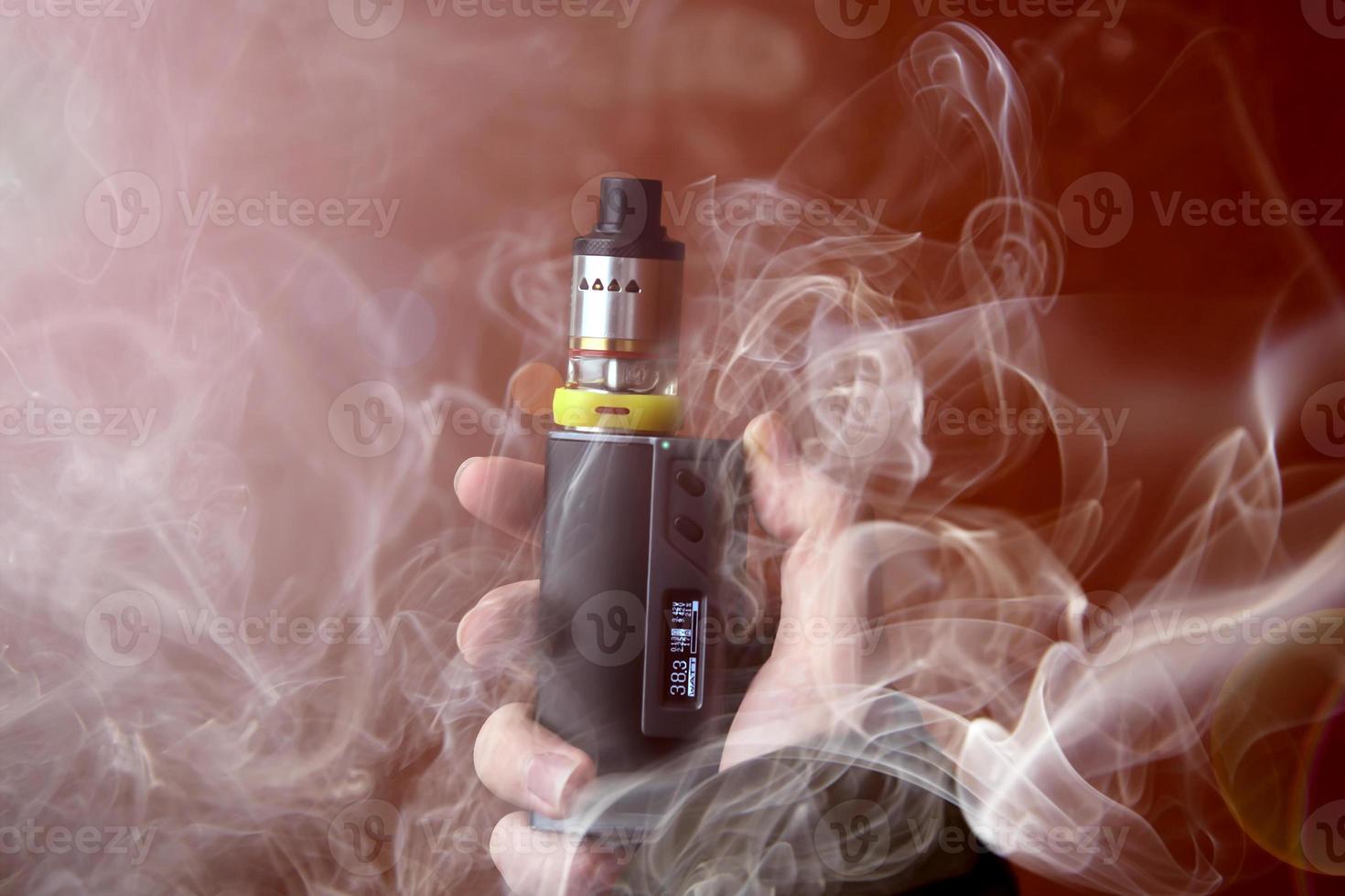 elektronisk cigarett i rök på brun bakgrund foto