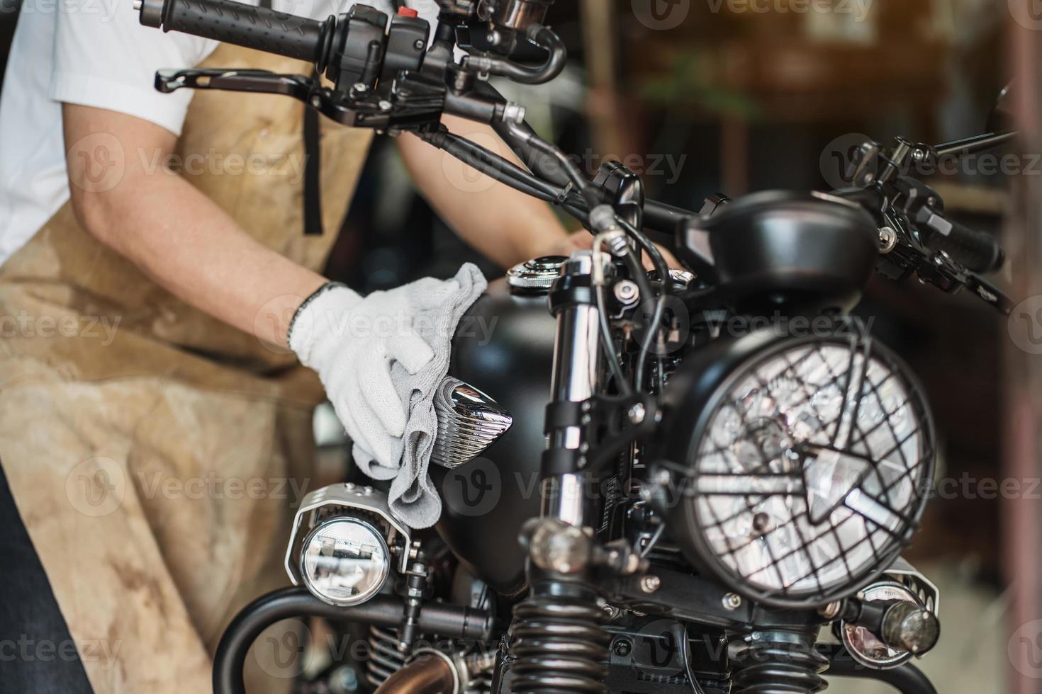 biker man rengöring motorcykel, polerad och beläggning vax på bränsletanken i garaget. motorcykel underhåll och reparation koncept. foto