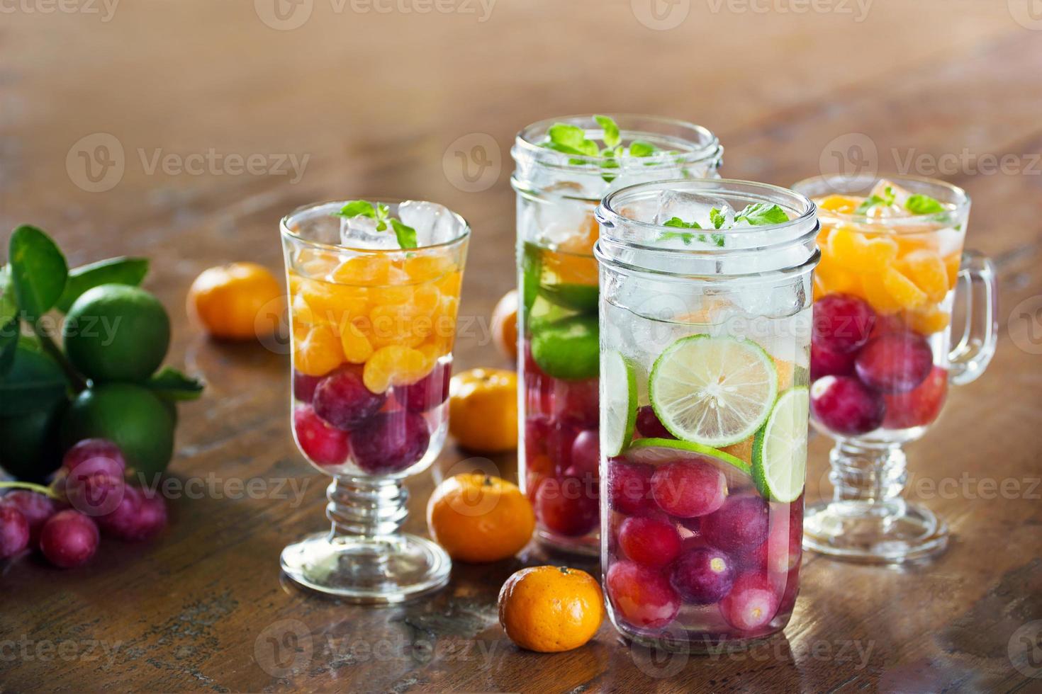 glas uppfriskande detox diet drycker av mix frukter på trä bakgrund, infusion vatten, hälsosamt koncept foto