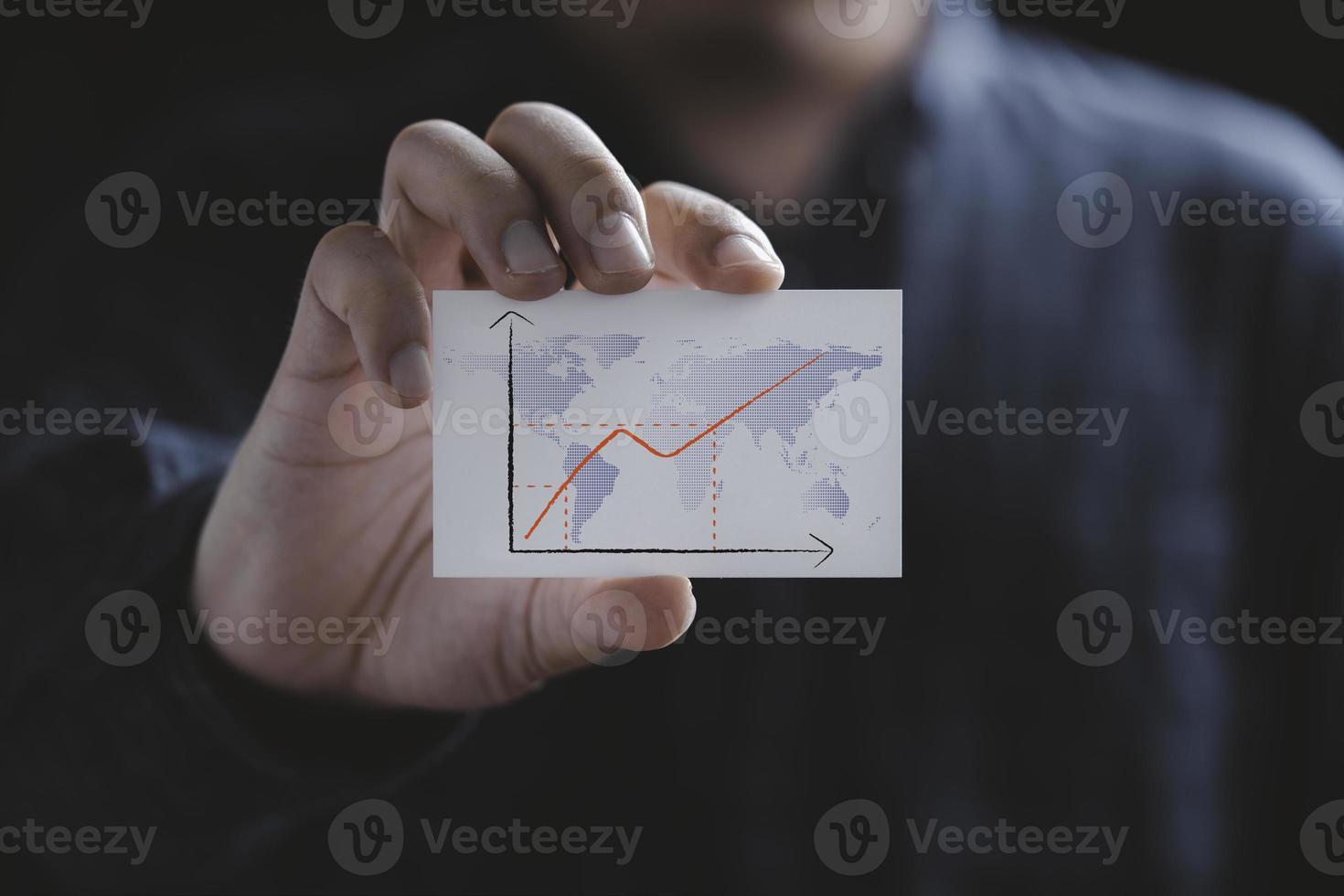 affärsman håller vitt papper med ökande graf och världskarta för ekonomiinflation efter covid-19 pandemi koncept. foto