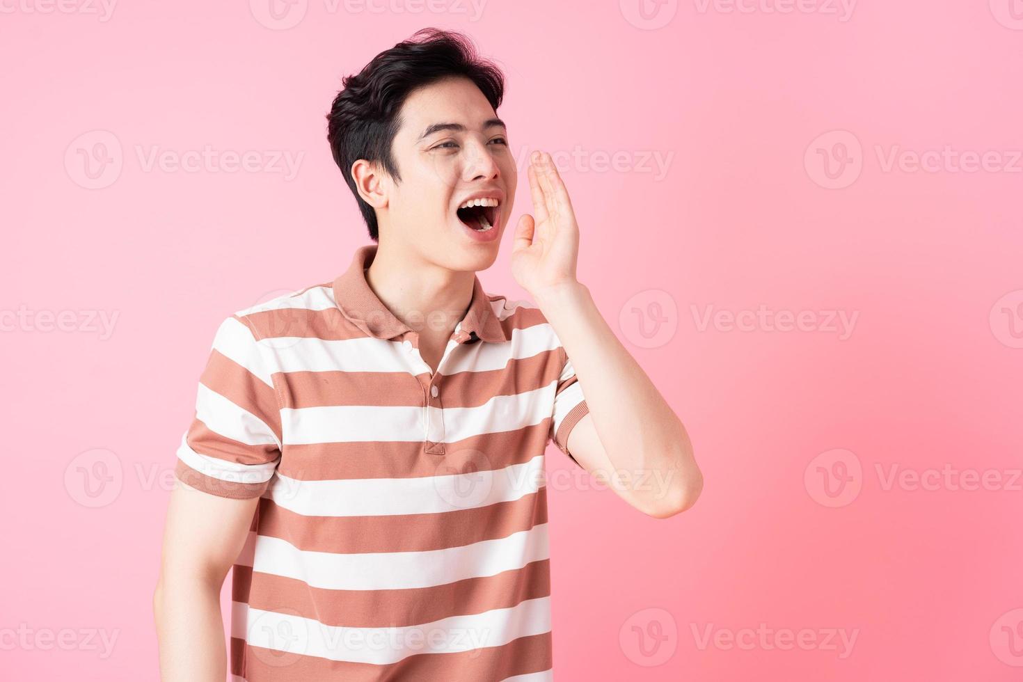 ung asiatisk man poserar på rosa bakgrund foto