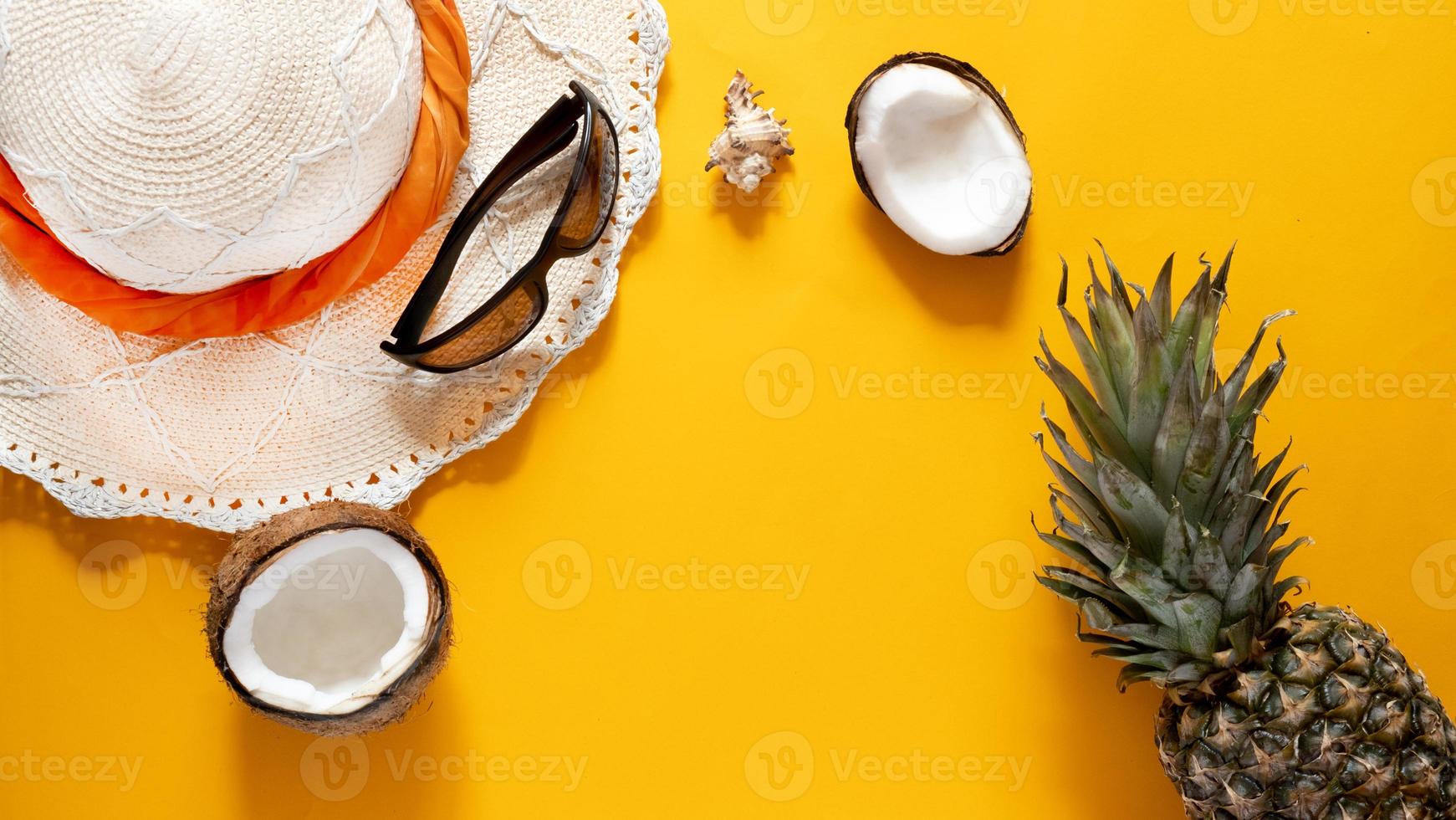 sommarkomposition. kokos, hatt och solglasögon på en gul bakgrund med kopia utrymme. semester koncept. toppvy foto