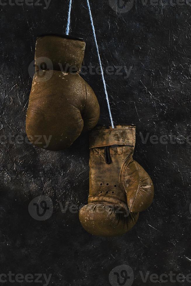 gamla bruna boxningshandskar som hänger på väggen. foto