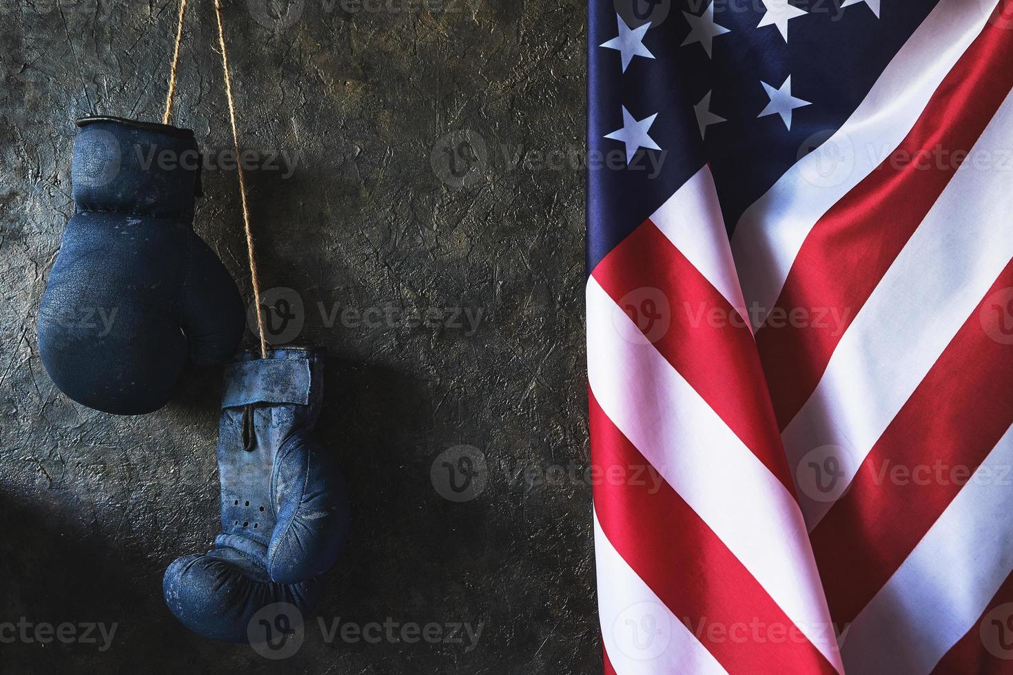 gamla boxningshandskar hänger på väggen bredvid USA:s flagga. foto