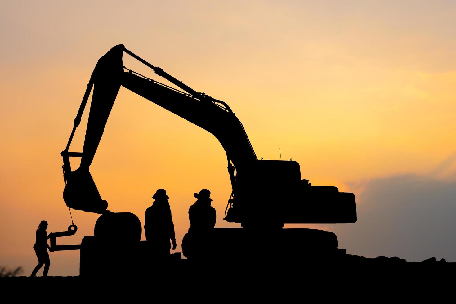 siluett av byggarbetsplatsen med vägbyggnadsarbetare och grävmaskin foto