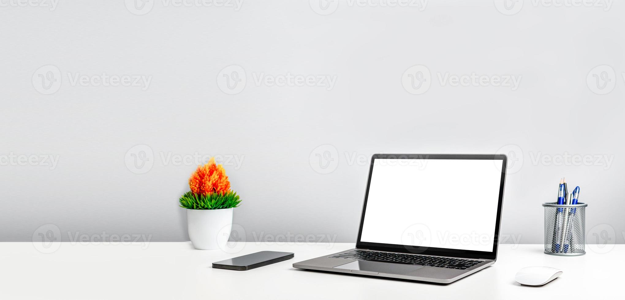tom vit skärm laptop på ett vitt bord på kontoret. fungerande koncept med teknik smartphones, anteckningsbok, internet. kopieringsutrymme till vänster för design eller text, närbild, grå och suddig bakgrund foto