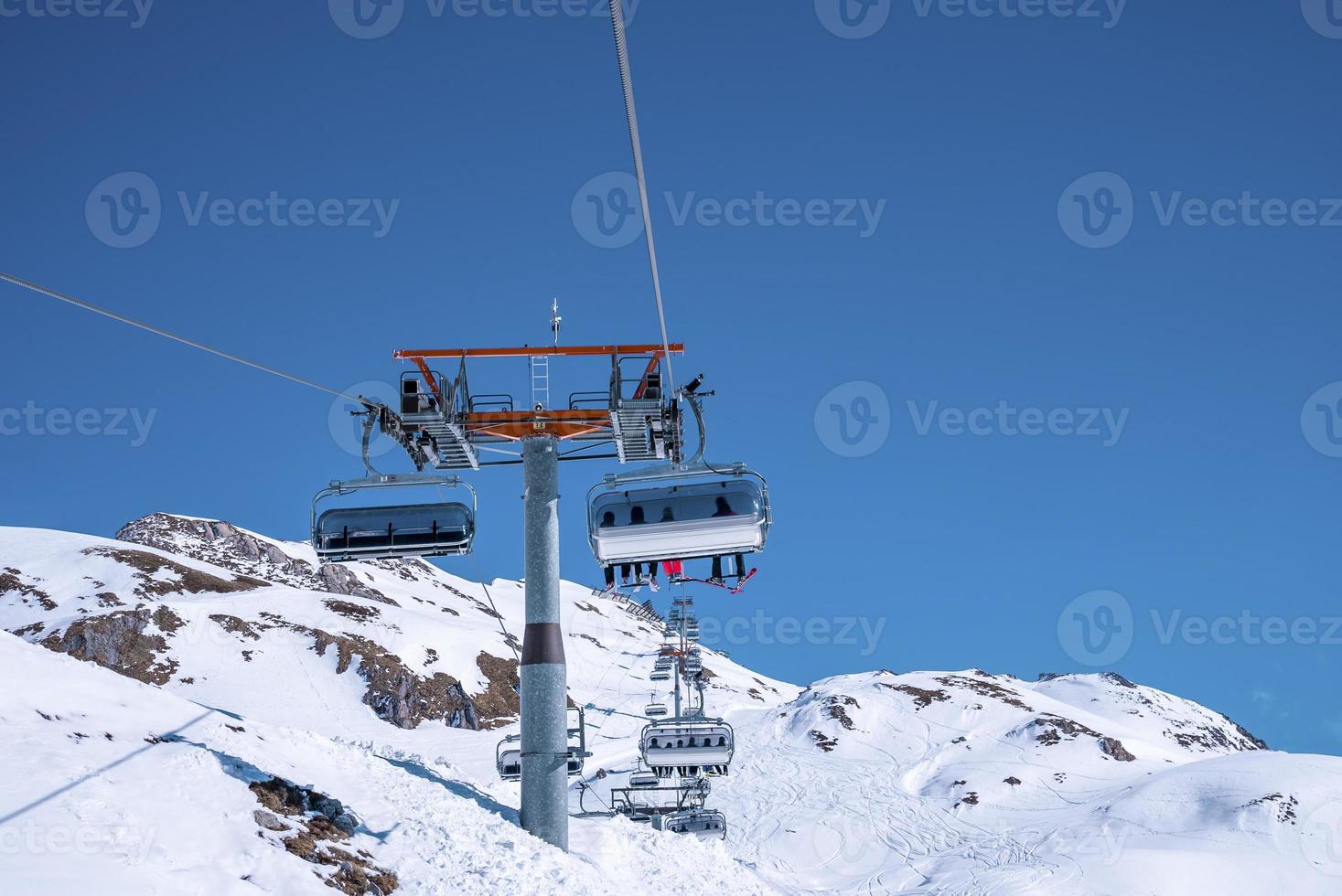 linbanor som reser över snötäckta bergssluttning mot klarblå himmel foto