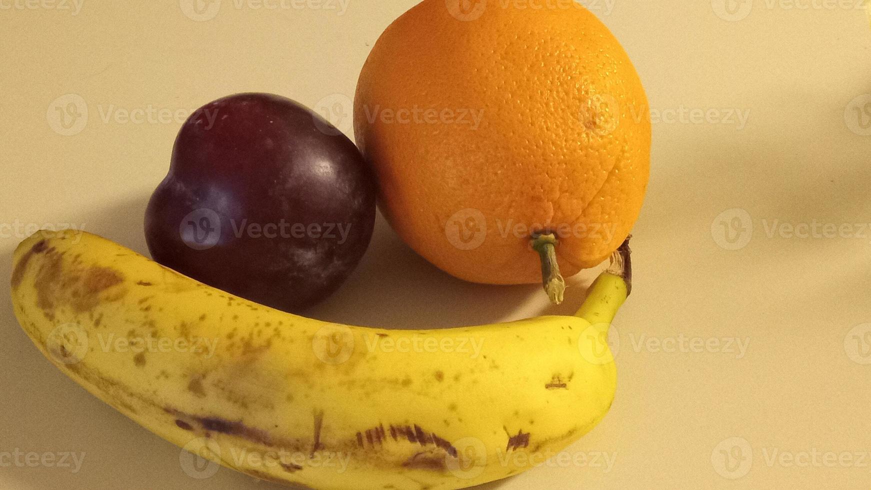 frukten av plommon, apelsin och banan foto