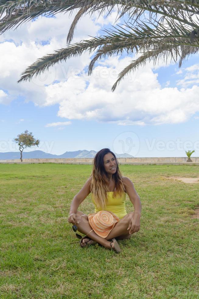 porträtt av en latinsk kvinna som ler, har roligt, på semester i mallorca poserar en varm vårsommardag, under en palm, semesterkoncept foto