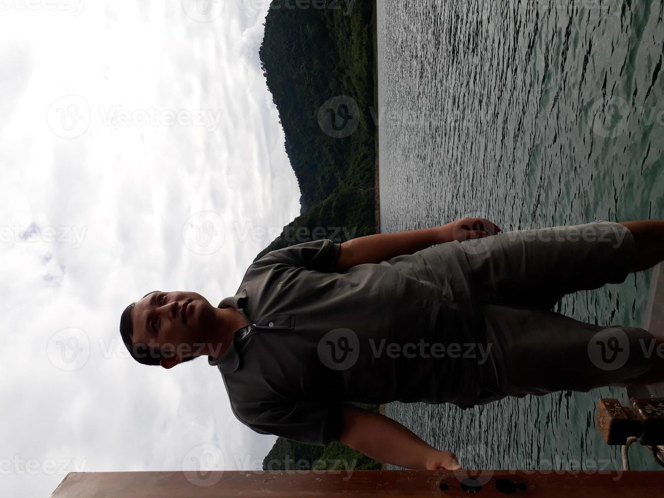 stiliga män som sitter på båten och letar efter utsikt är konceptresor. asiatiska män som reser med båt och ser sig omkring i bergen över den vackra sjön. foto