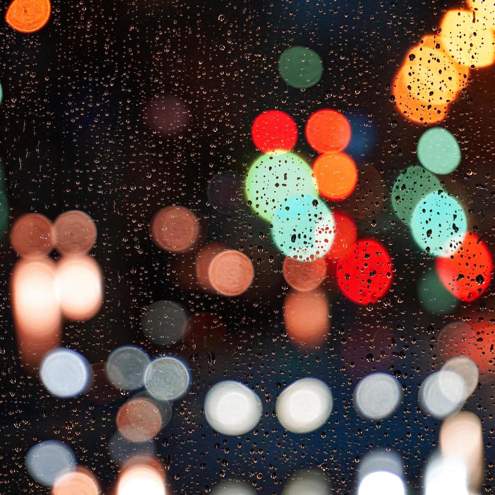 regndroppar på fönstret och gatubelysning på natten i staden foto