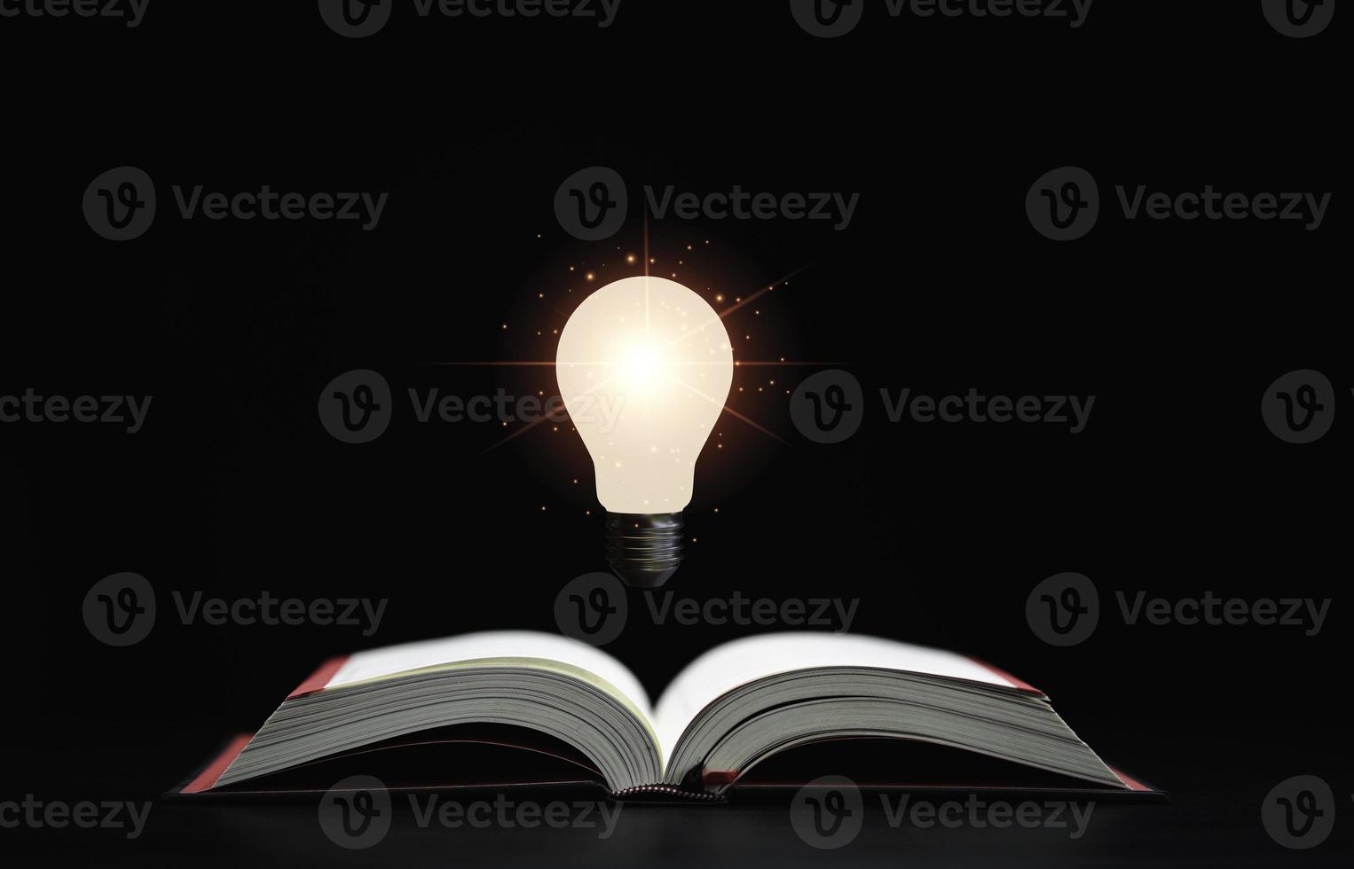 glödande lampa svävar ovanför en öppen bok på mörk bakgrund som är en symbol för studier, en kunskap hjälper till att lösa problem och lösningskoncept. foto
