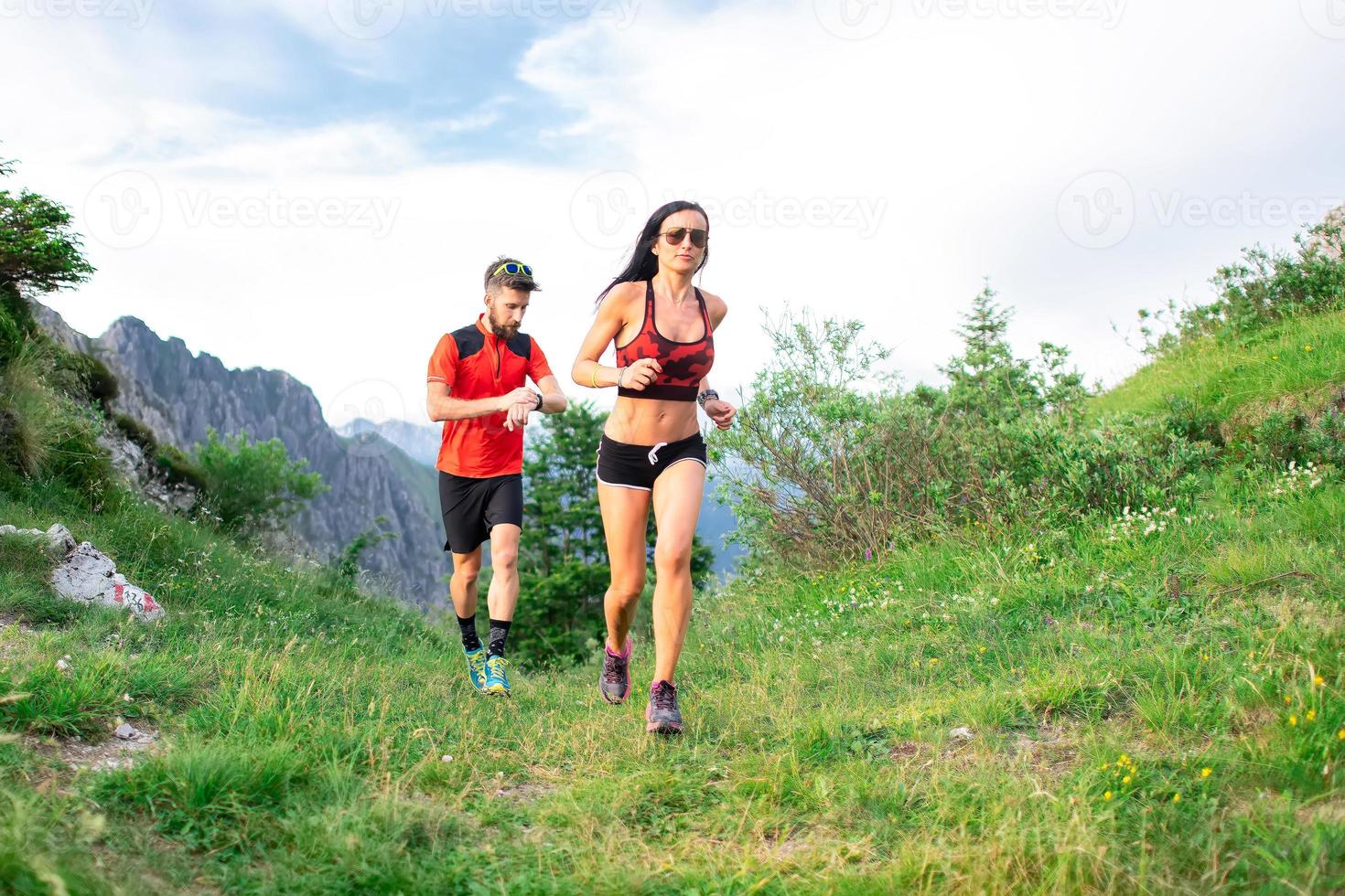 atletisk tränare mäter tiden för en kvinnlig idrottskvinna i berget foto