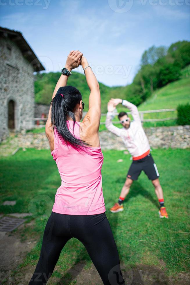 personlig tränare gör kvinna utomhus atletiska övningar foto