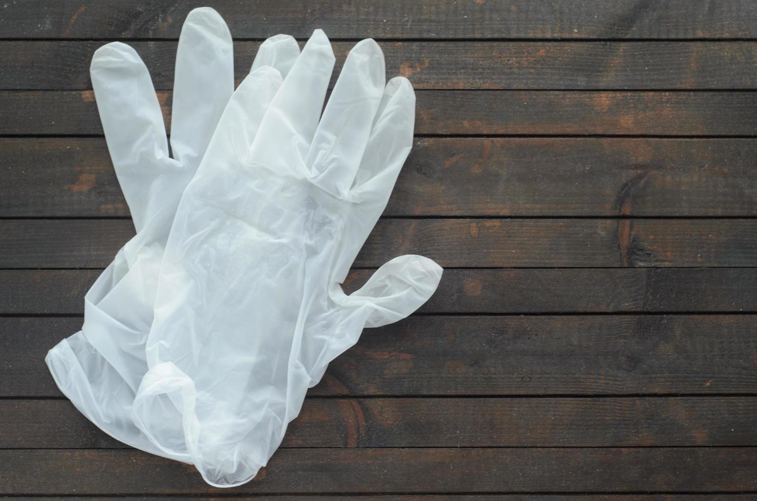 vita engångshandskar på mörk trä bakgrund. handskar för skydd mot coronavirus. foto