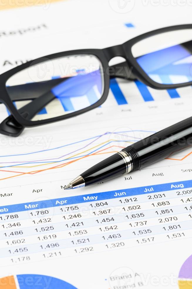 försäljningsrapportanalys med penna och glasögon foto
