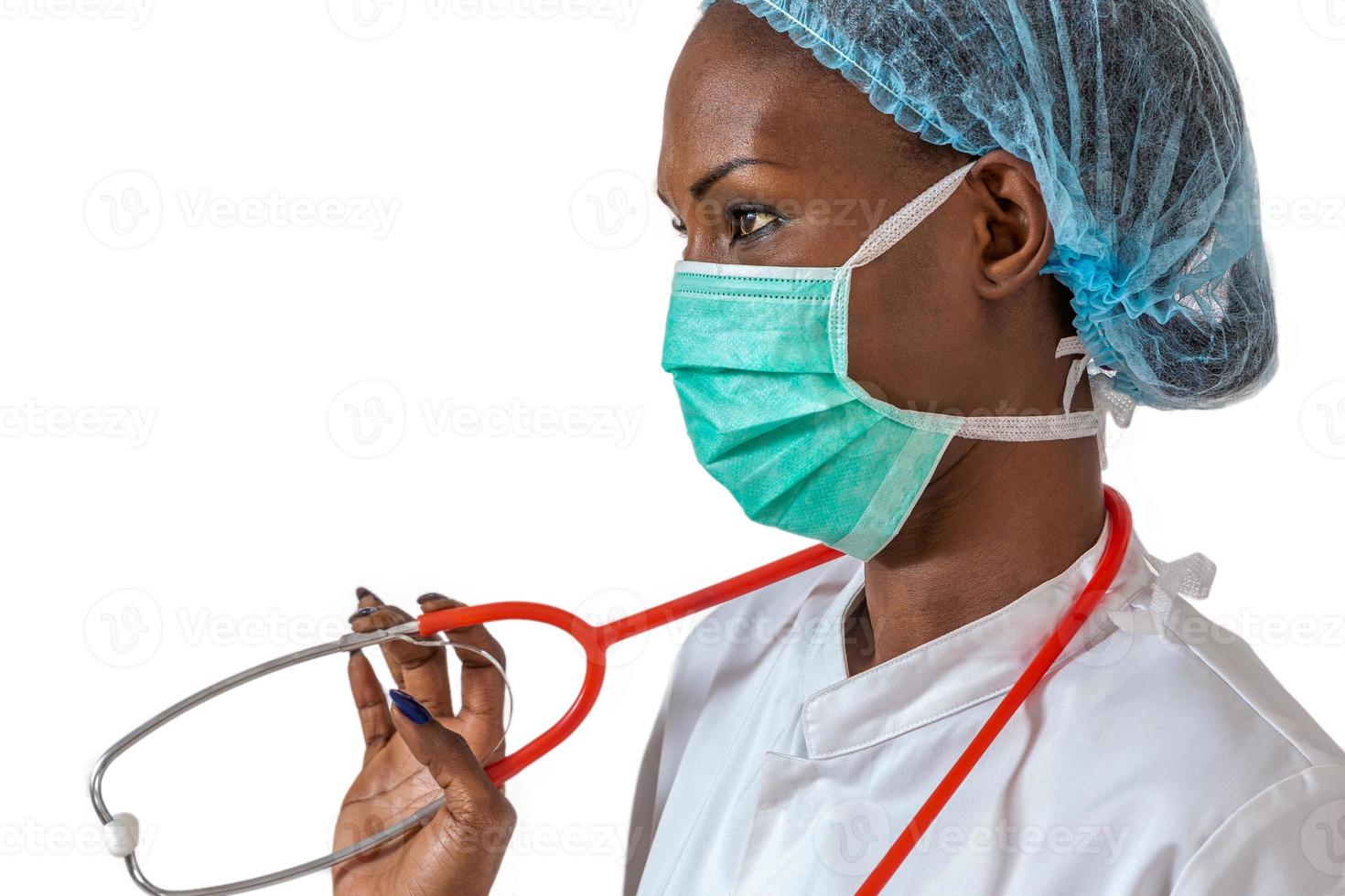 kvinnlig amerikansk afrikansk läkare, sjuksköterska kvinna som bär medicinsk kappa, mössa, med stetoskop och mask. foto