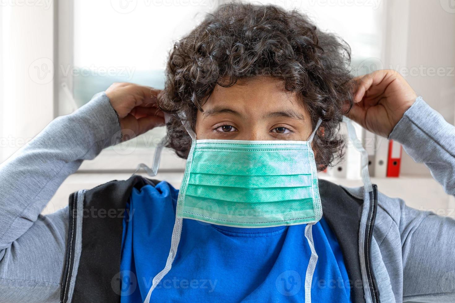 Pojken håller en medicinsk skyddsmask ansiktsmask mot virusepidemi influensa coronavirus ansiktsmask för skydd foto