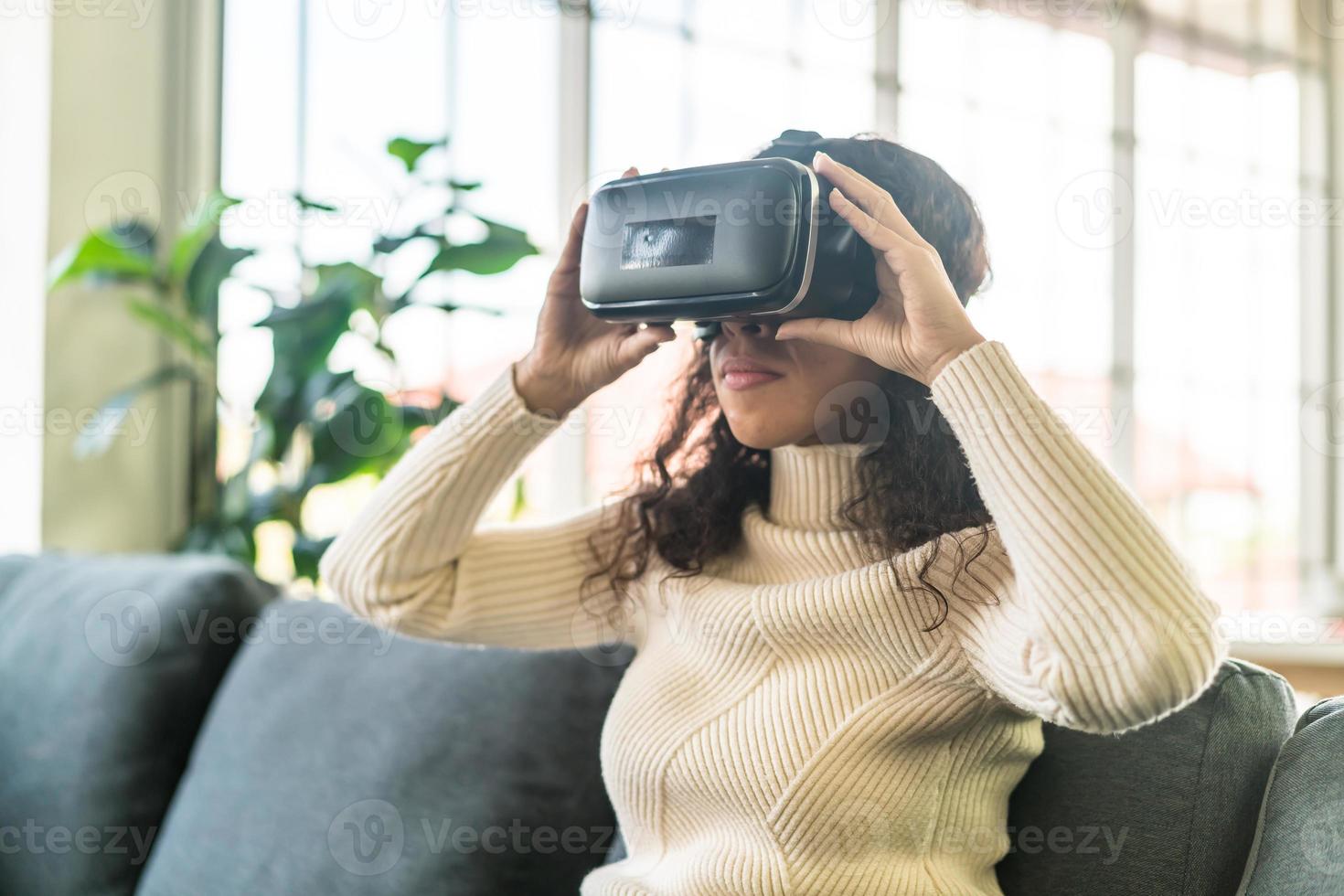 latinsk kvinna som använder ett virtual reality-headset på soffan foto