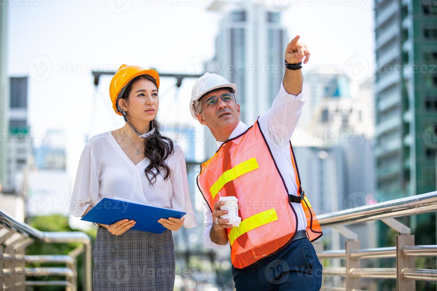 ingenjören och affärskvinnan kollar på urklipp på byggarbetsplatsen. begreppet teknik, byggande, stadsliv och framtid. foto