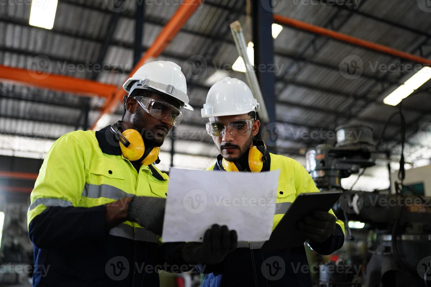underhållsingenjörer arbetar framför den automatiska reparationen av cnc-maskiner på en checklista för underhåll vid produktionslinjen. foto