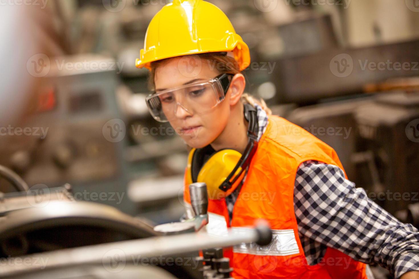 kvinnlig arbetare arbetar på fabriksplatsen kontrollera maskin eller produkter på plats. ingenjör eller tekniker som kontrollerar material eller maskin på anläggningen. industri och fabrik. foto
