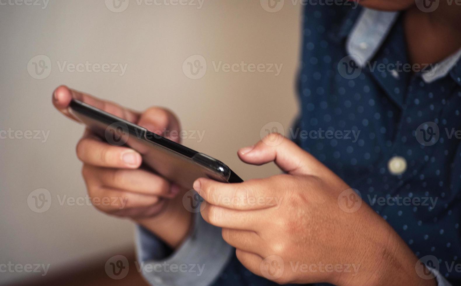 pojke spelar spel på smartphones, pojke hand som håller en smartphone foto