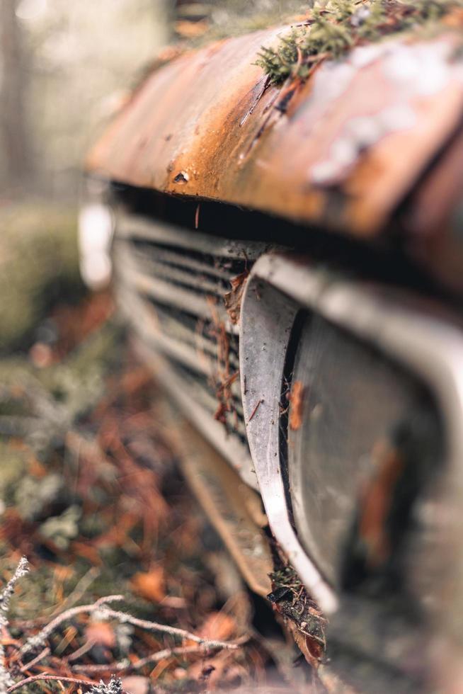 gammal övergiven och rostig bil i en skog täckt av mossa foto