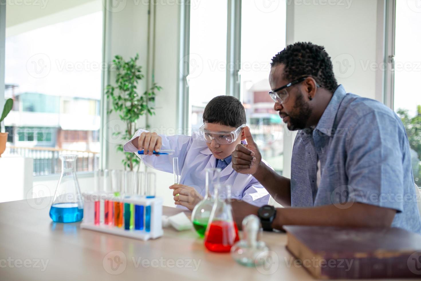 elever blandar kemikalier i bägare. entusiastisk lärare förklarar kemi för barn, kemistudent visar nytt experiment för lärare i naturvetenskap foto