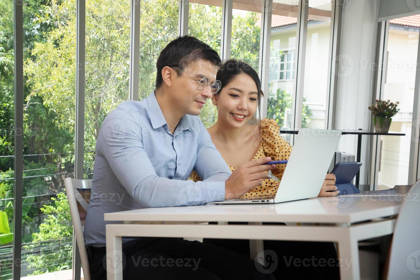 olika affärskollegor sitter vid ett skrivbord på ett modernt kontor och pratar tillsammans över en bärbar dator foto