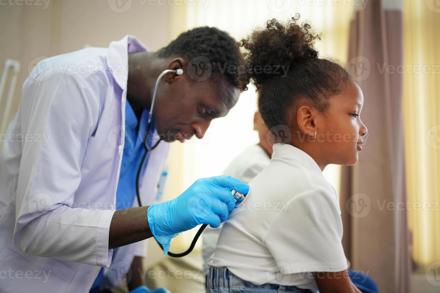 svart hudläkare kollar upp barnkroppen på kliniken. foto