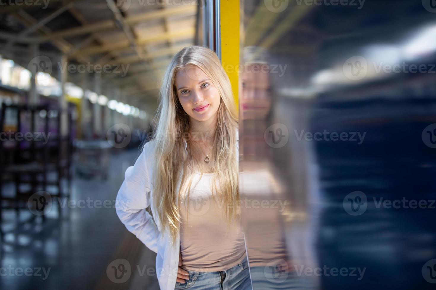 porträtt av en vacker blond ung kvinna som står vid tåg. foto