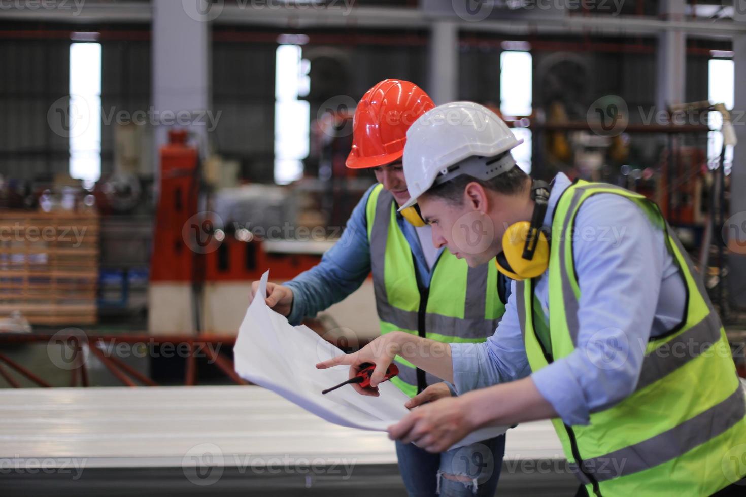 män industriingenjör som bär skyddshjälm när de står i en tung industrifabrik. underhållet av att arbeta på industriella maskiner och kontrollera säkerhetssystemets installation i fabriken. foto