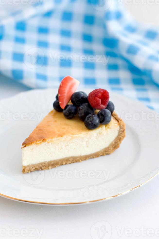 en bit av new york cheesecake på en vit platta på en blå bakgrund, närbild foto