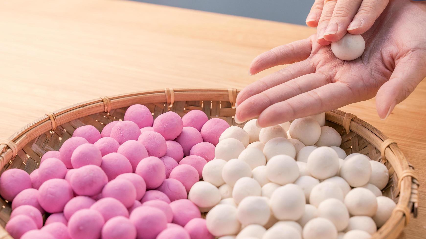 en asiatisk kvinna gör tang yuan, yuan xiao, kinesisk traditionell mat ris dumplings i rött och vitt för månens nyår, vinterfestival, närbild. foto