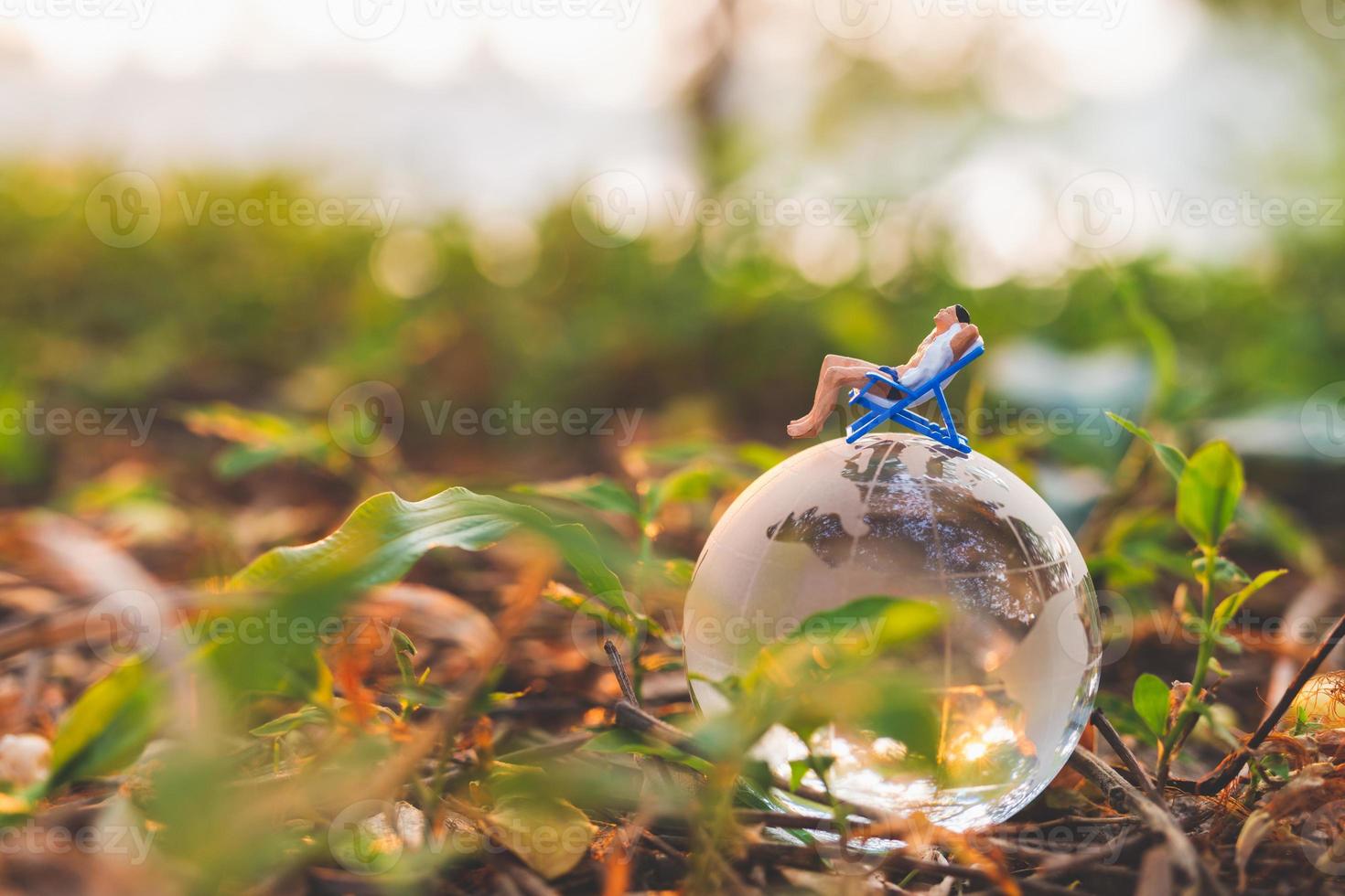 miniatyr människor som solar på kristallklotet i parken foto