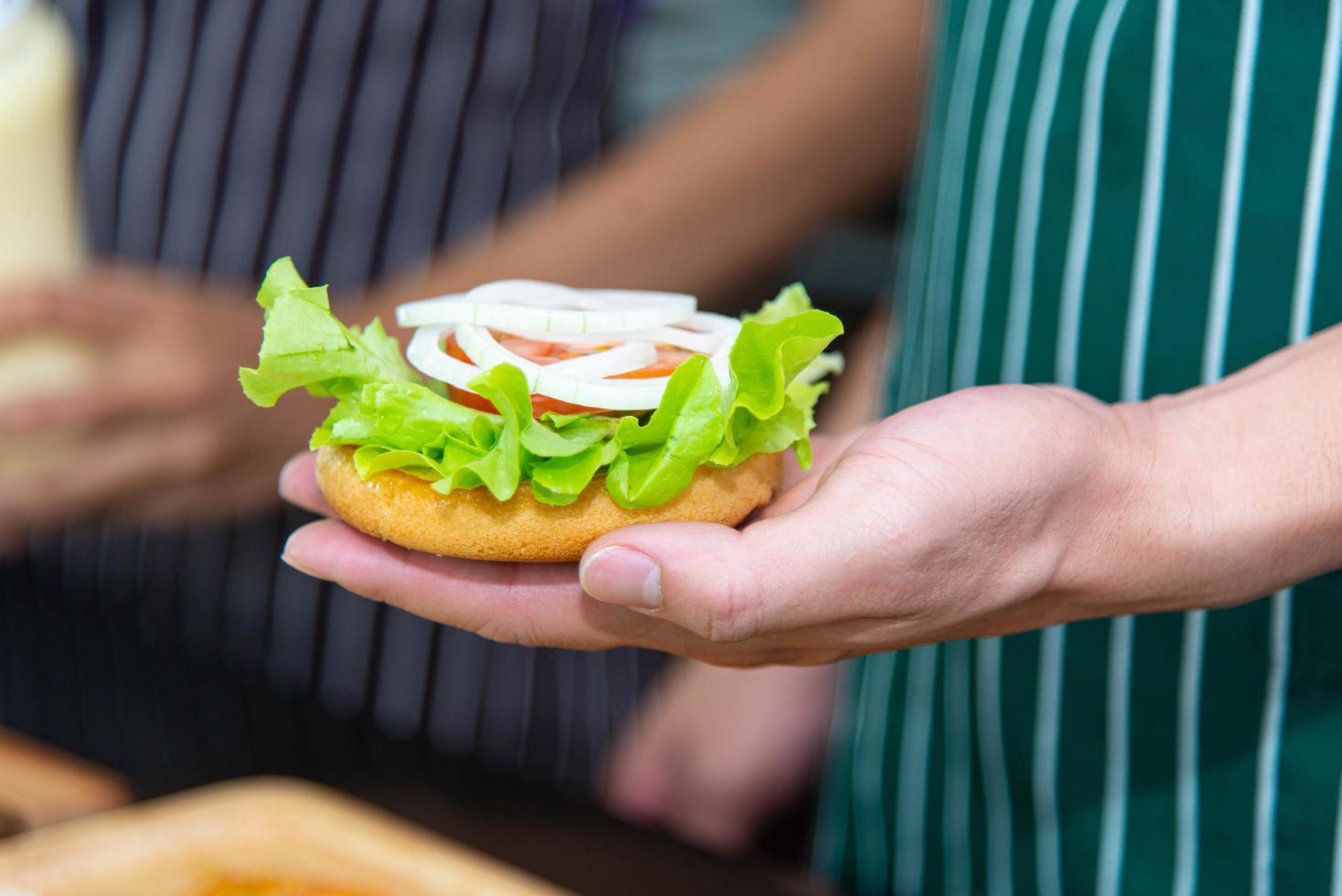 kocken förbereder bröd lök tomat grönsaker och gör hamburgare i köket. foto