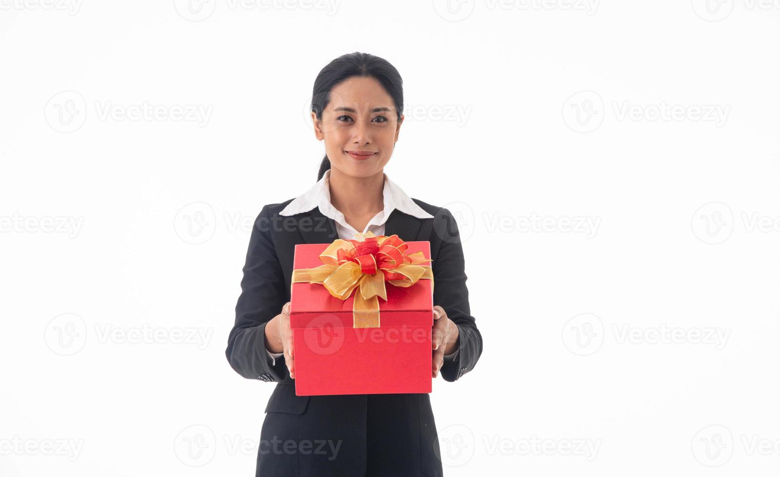 porträtt ung vacker leende glad kvinna bär svart kostym som håller röd presentförpackning tittar på kameran på isolerad vit bakgrund. foto