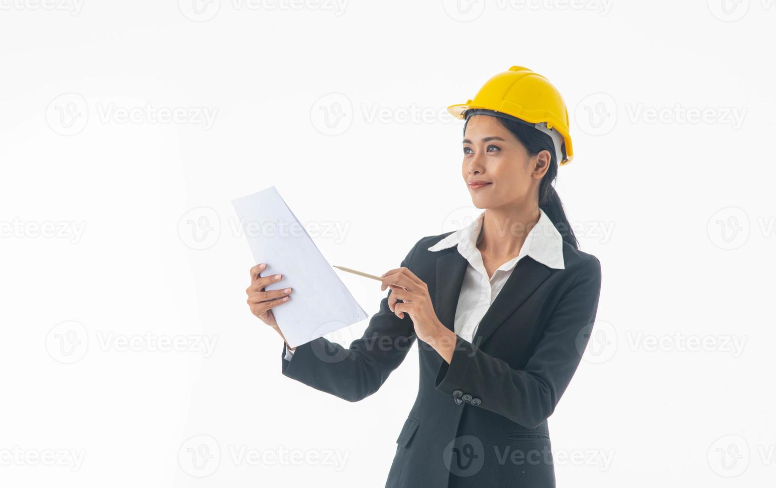 ung ingenjör kvinna bär svart kostym och gul skyddshjälm hålla anteckning på isolerade vit bakgrund. foto