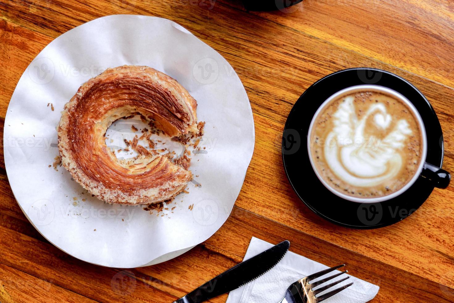 croissant och varm latte serveras på träbord foto