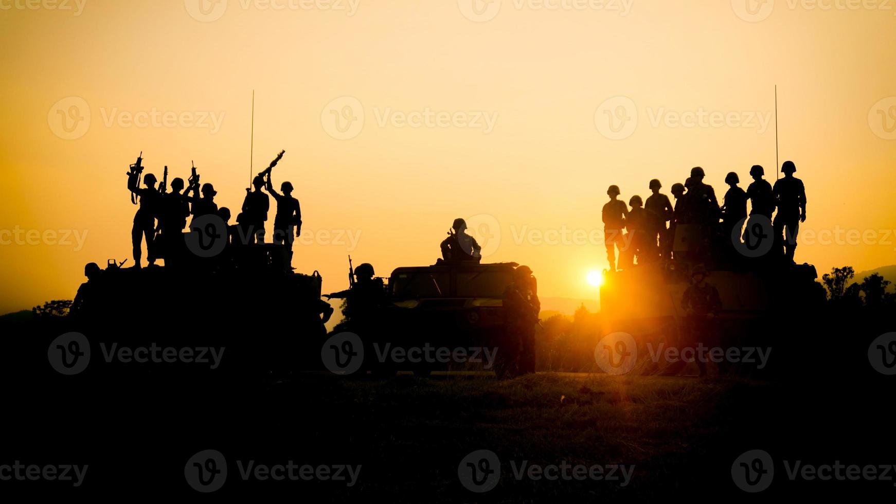silhuetter av armésoldater i dimman mot en solnedgång, marinteam i aktion, omringad eld och rök, skjutande med automatgevär och maskingevär, attackerande fiende foto