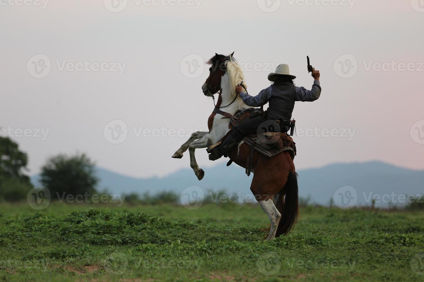 siluett cowboy på hästryggen mot en vacker solnedgång, cowboy och häst vid första ljuset, berg, flod och livsstil med naturligt ljus bakgrund foto